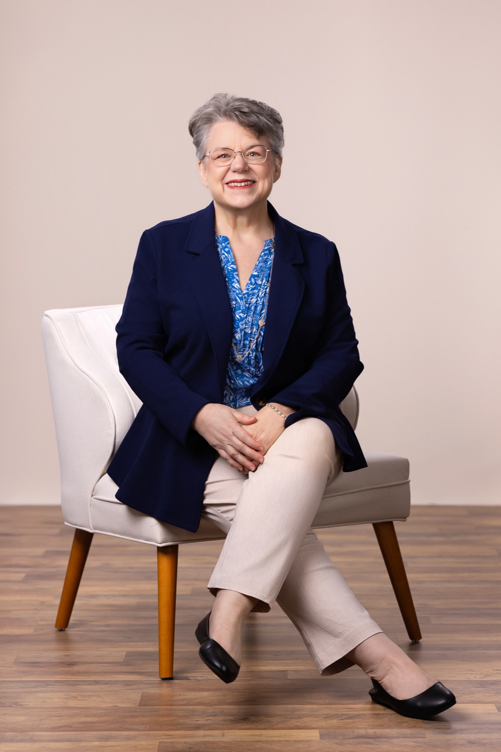 Wendy Cary - 202502 - 2x3 19 Wendy Cary sitting in a chair with her legs crossed and hands resting in her lap
