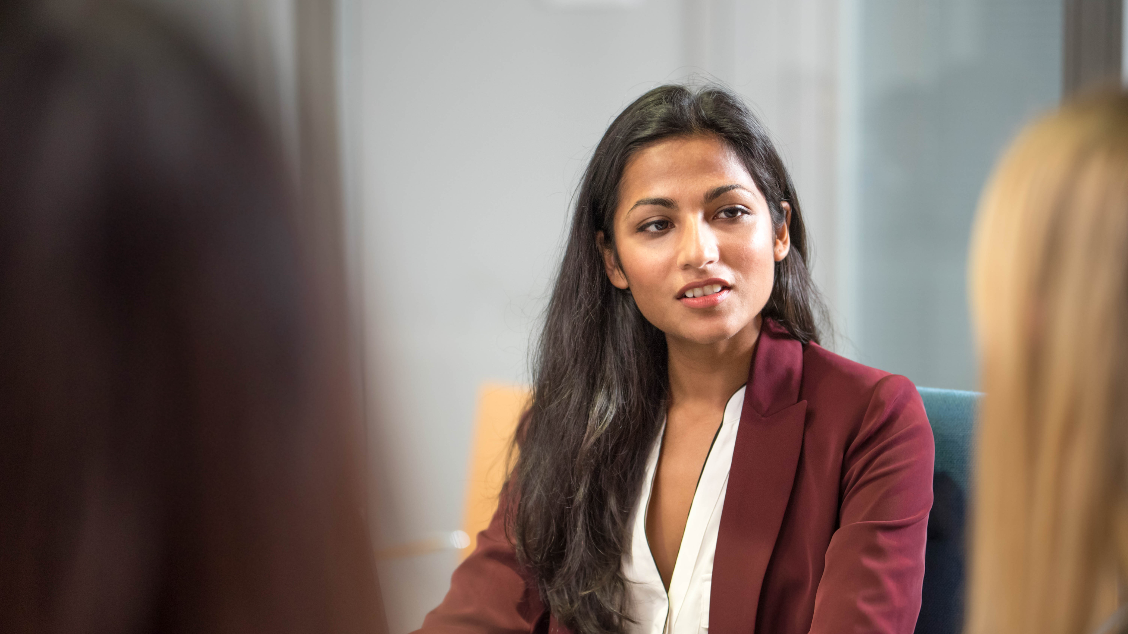 Woman speaking with colleagues during a leadership meeting.